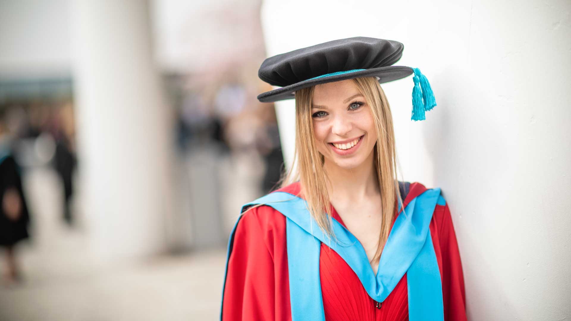 a girl smiling in a graduation gown and cap
